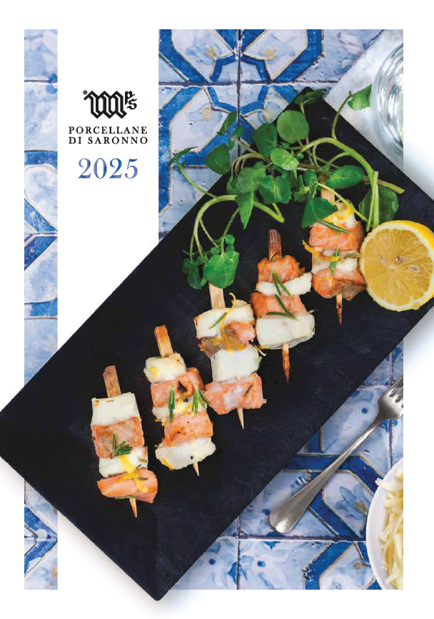 Spiedini di frutti di mare su un piatto nero con limone e verdure, su una tovaglia a mosaico blu con il logo 2025.
