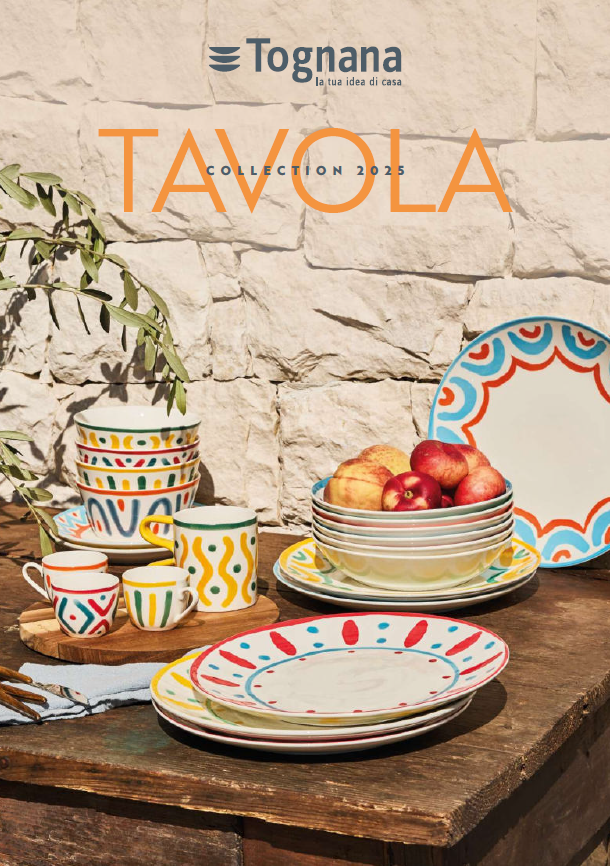 Stoviglie colorate di Tognana esposte su un tavolo rustico con ciotole, piatti, tazze e frutta.