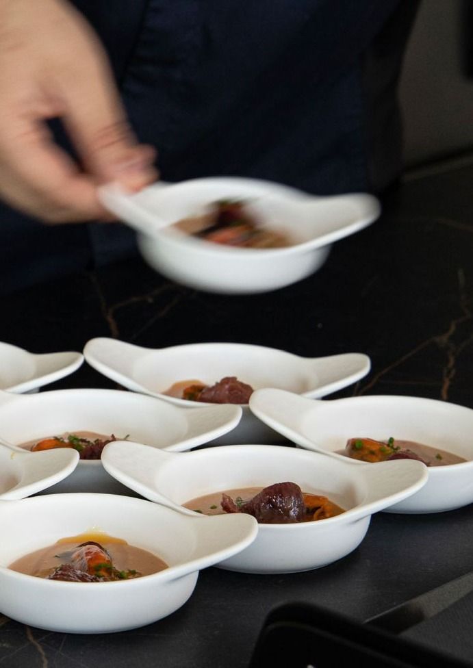 Ciotole bianche da antipasto con il cibo servito su un tavolo scuro.