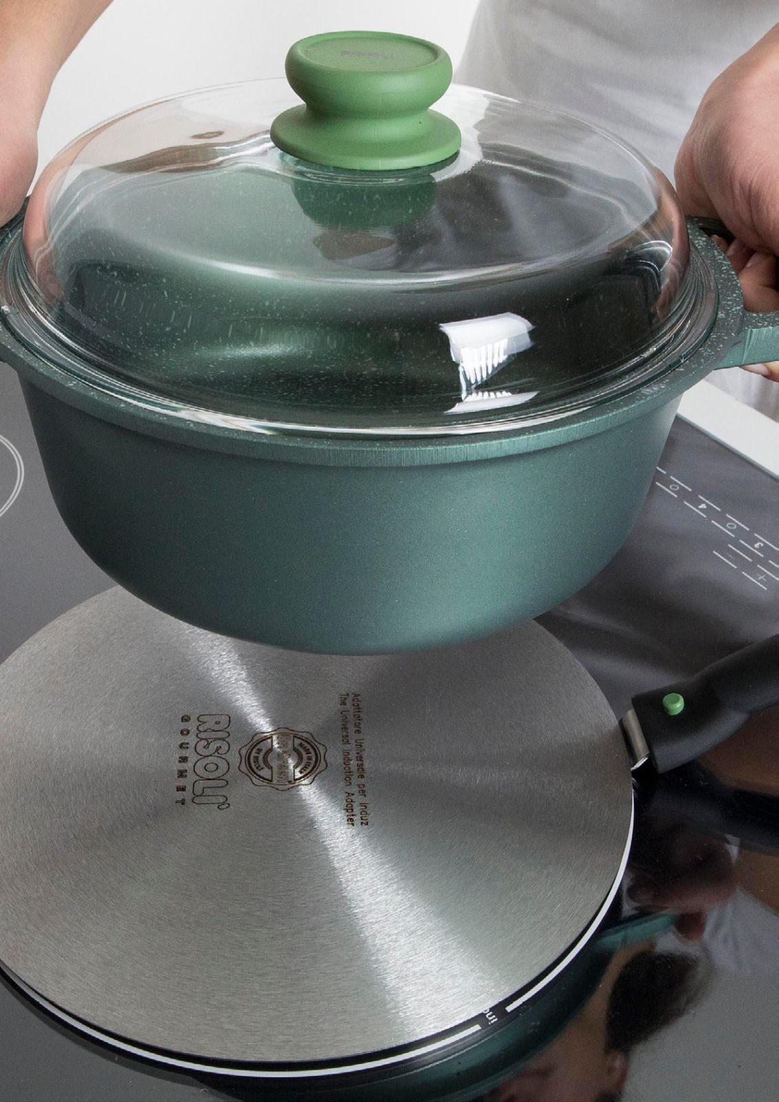 Pentola con coperchio verde su un fornello, tenuta con entrambe le mani.