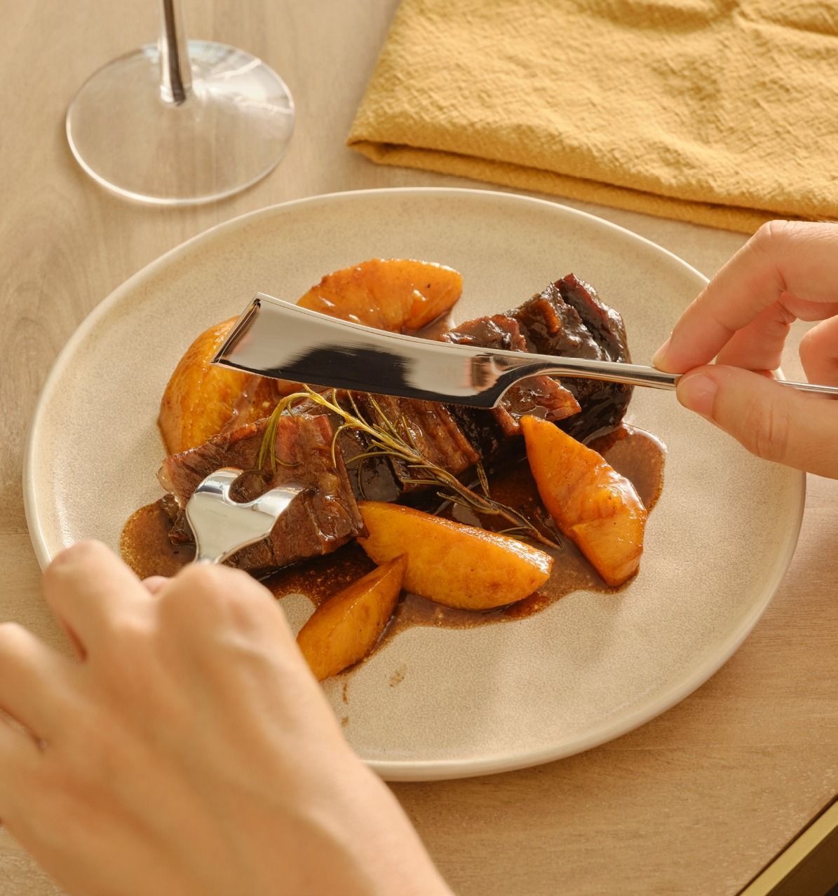 Carne arrosto con carote impiattata su un tavolo, tagliata con coltello e forchetta