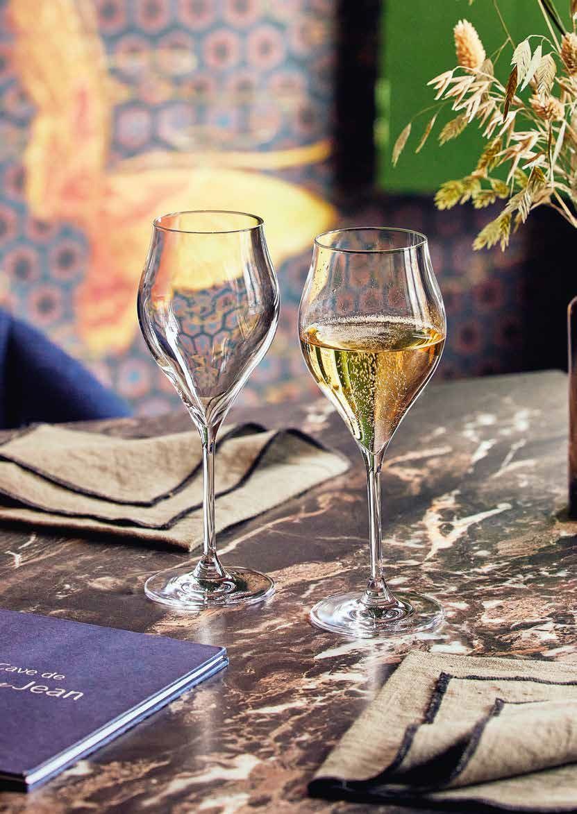 Due calici da vino su un tavolo illuminato da candele, con tovaglioli e menù, nell'accogliente atmosfera di un ristorante.