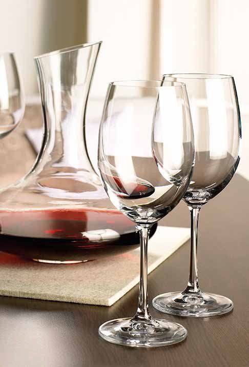 Una caraffa per il vino e due bicchieri vuoti su un tavolo, con un libro sui vini sotto.