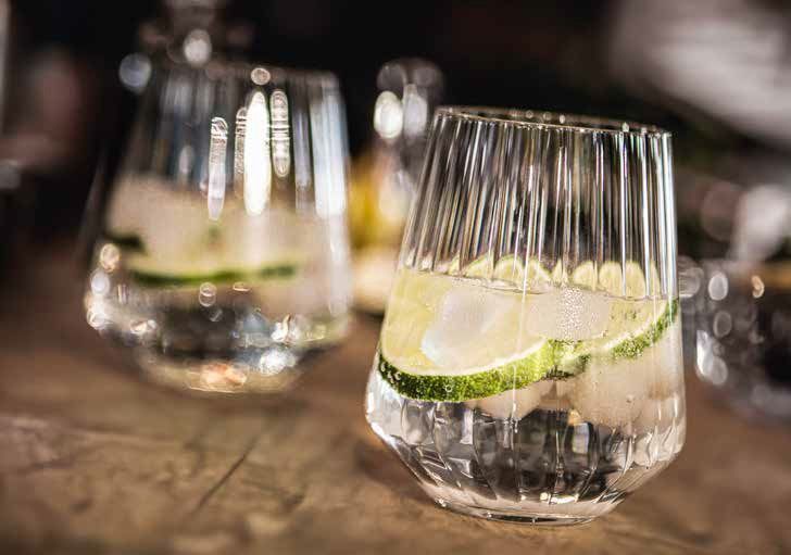 Due bicchieri di bevanda trasparente con fette di lime su un tavolo da bar.