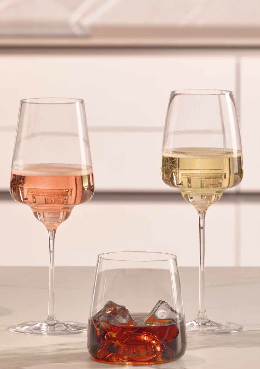 Due calici da vino e un bicchiere basso di bevanda color ambra su un tavolo
