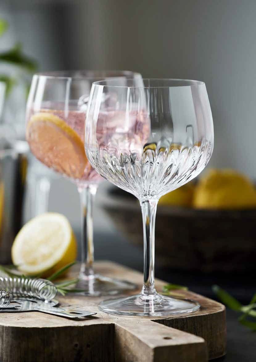Bicchieri da vino trasparenti su un rustico tagliere di legno con fette di limone e pompelmo nelle vicinanze.