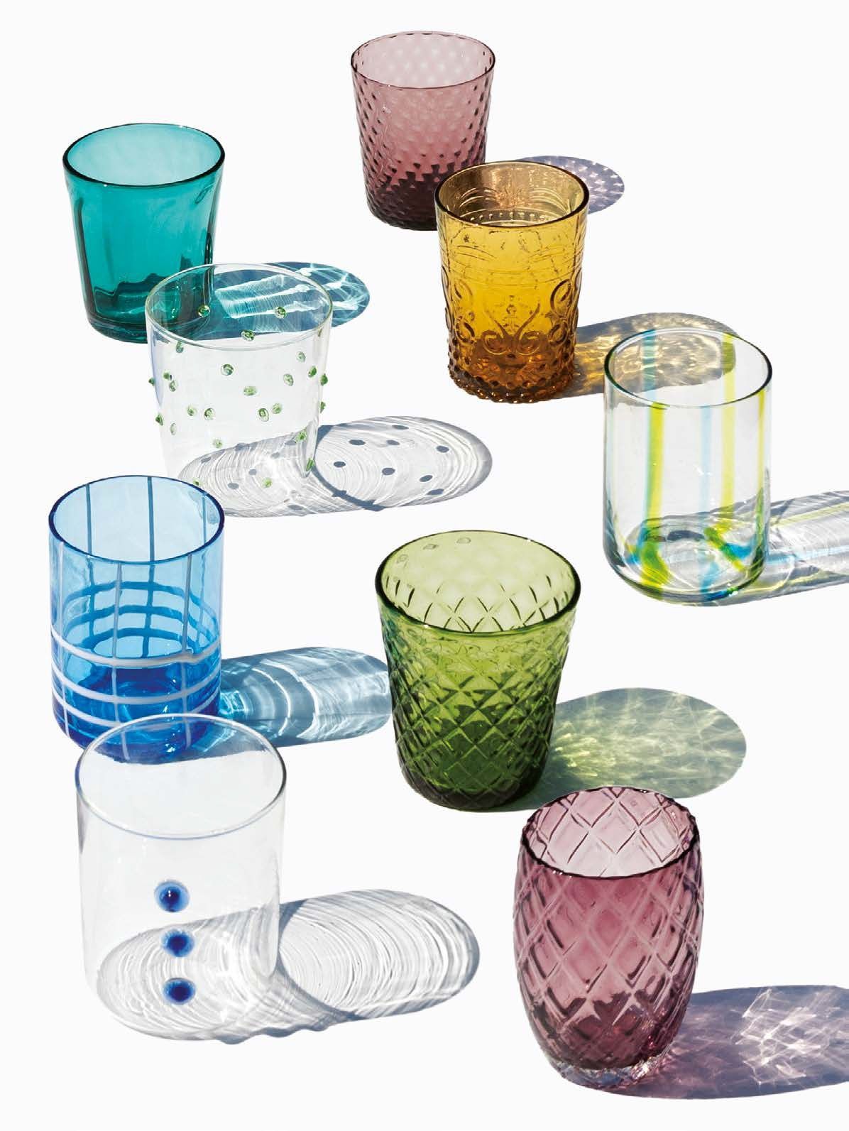 Vari bicchieri colorati e decorati, disposti su uno sfondo bianco.