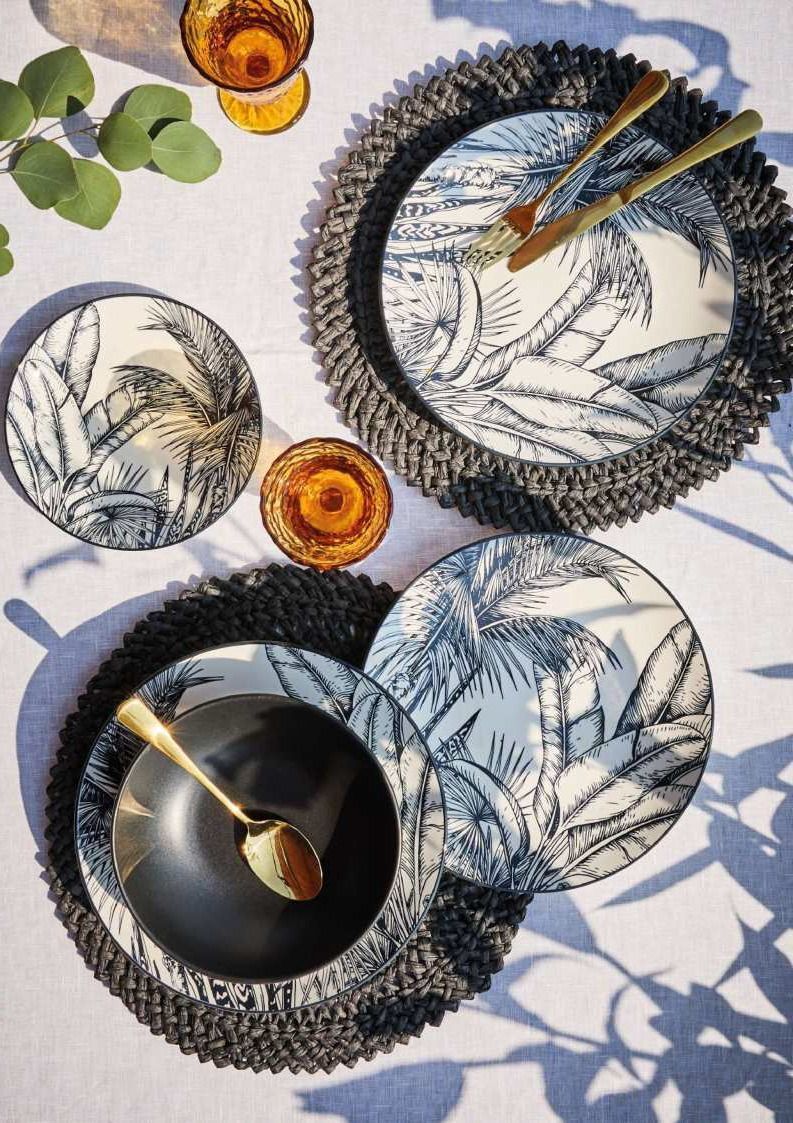 Due piatti decorati con bacchette e cucchiaio su un tavolo illuminato dal sole con fette di agrumi e foglie