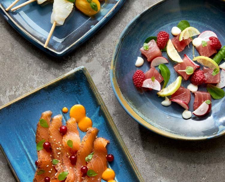 Assortimento di crostate e pasticcini alla frutta su piatti blu, guarniti con frutti di bosco e fette di agrumi.