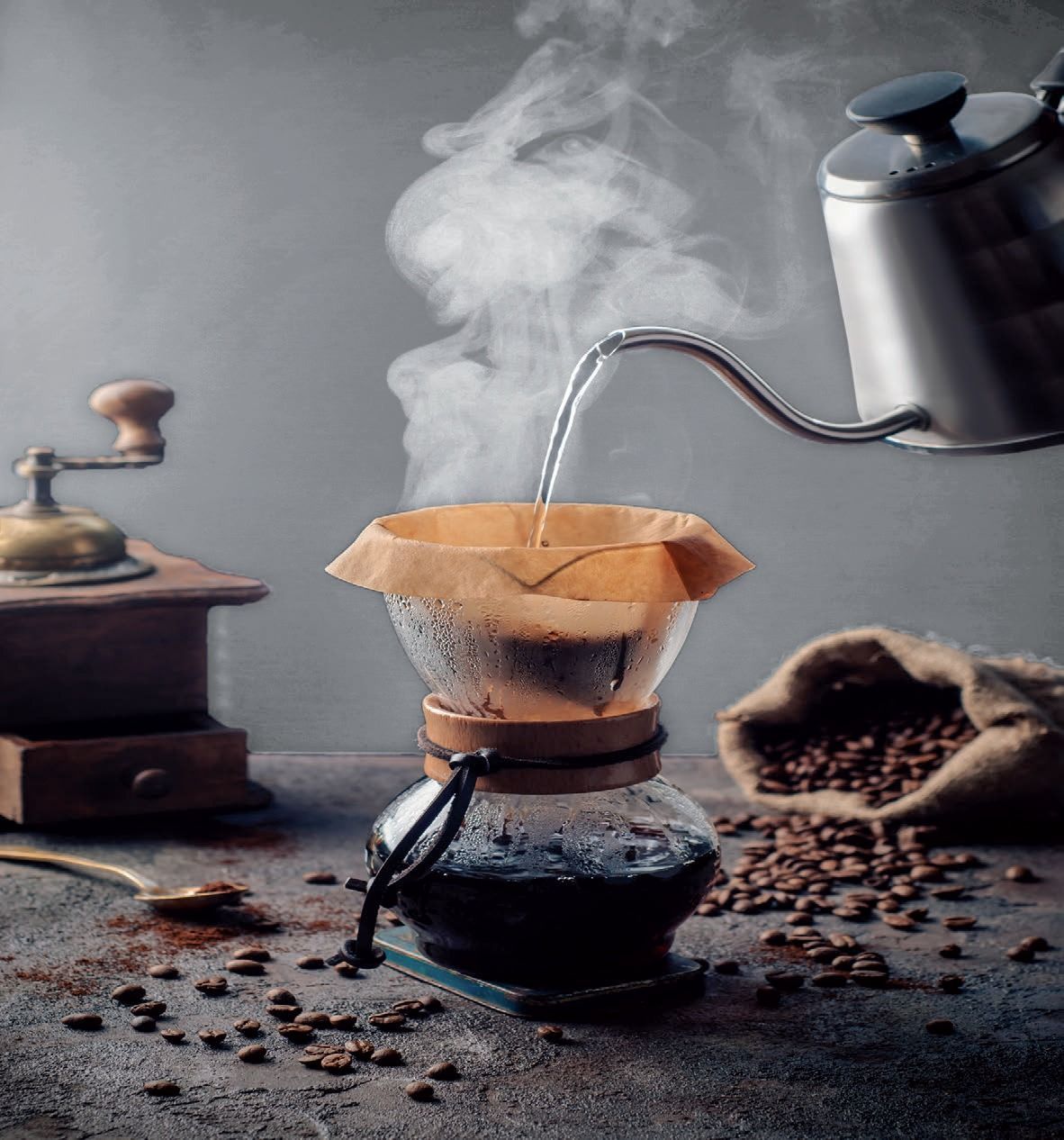Il vapore si sprigiona da una caffettiera a filtro mentre l'acqua calda viene versata in un filtro di carta su un tavolo scuro.