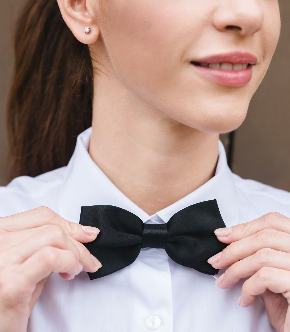 Una donna si sistema un papillon nero su una camicia bianca.