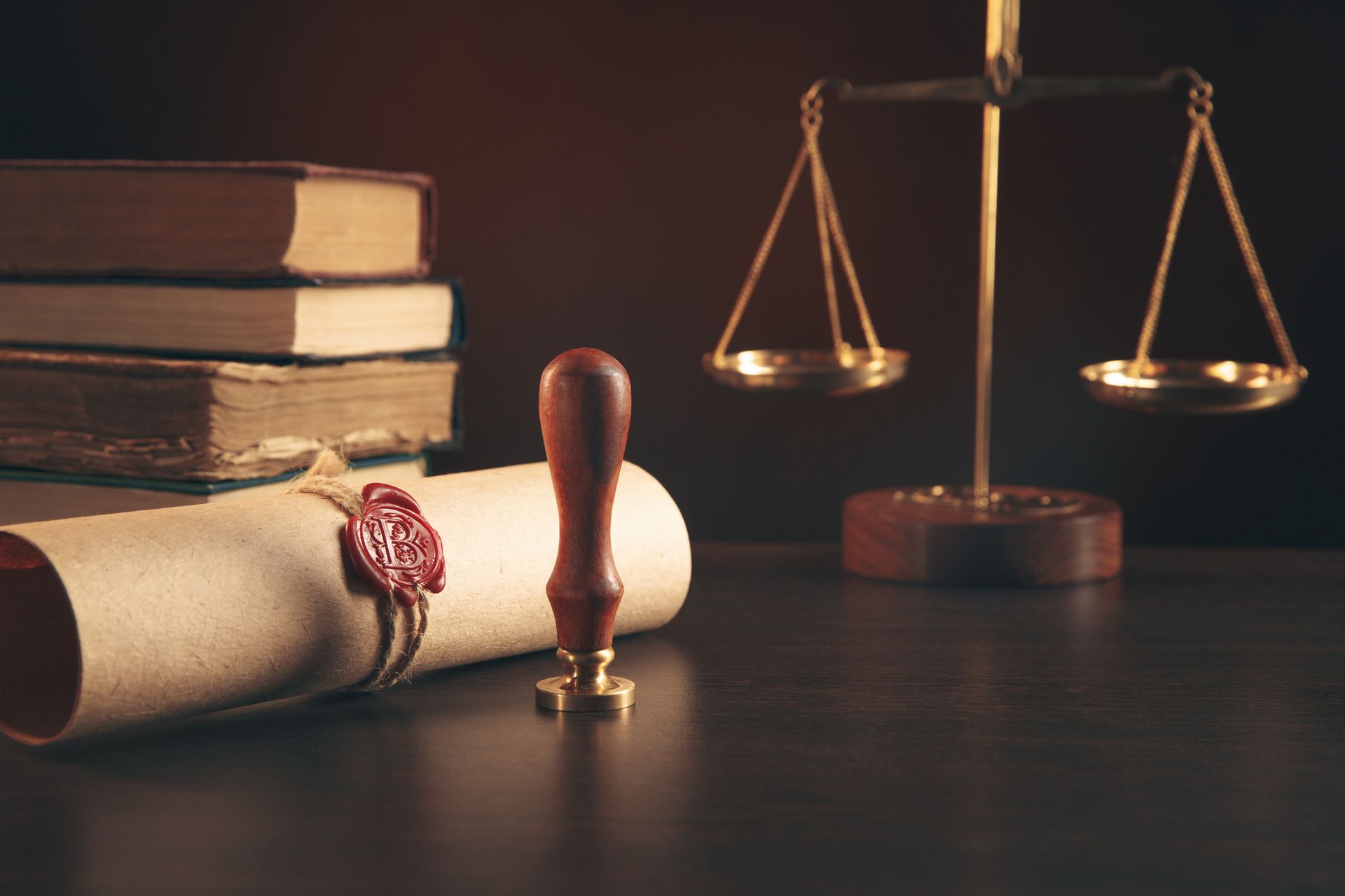 A stack of books , a seal , and a scale of justice on a table.