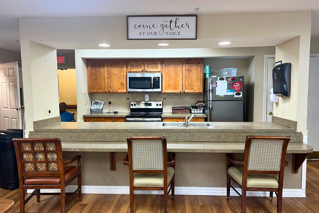 Hotel lobby kitchen with counter seating, wood cabinets, and stainless appliances