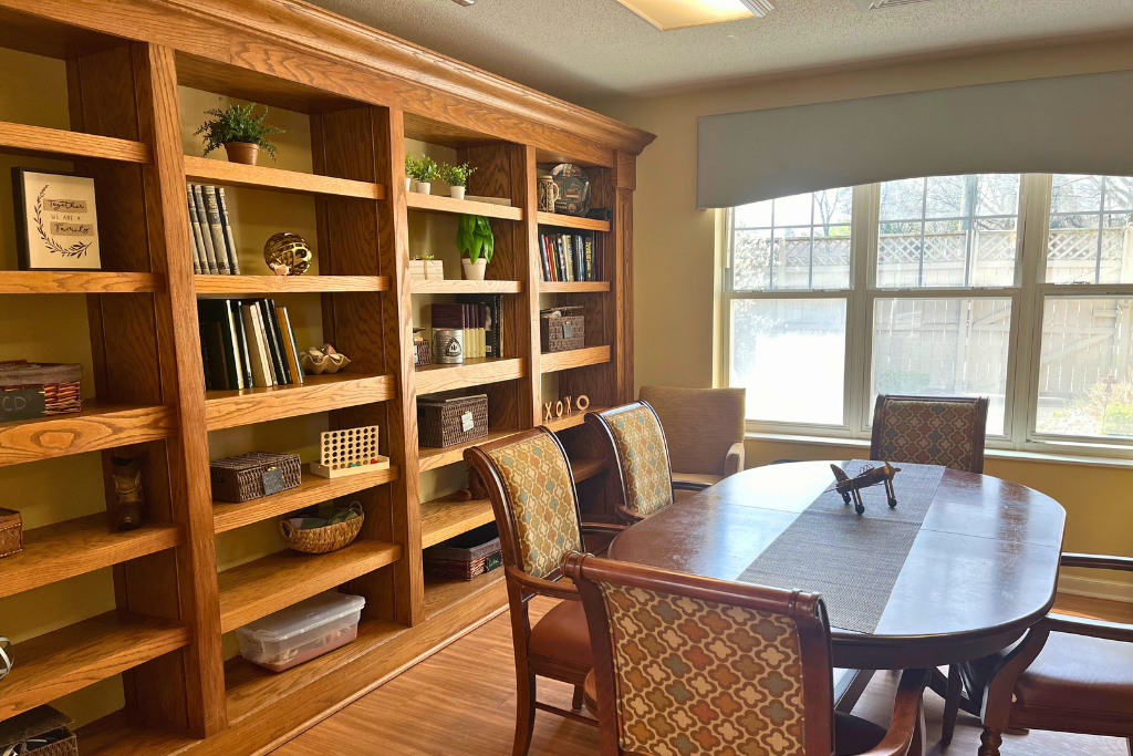 Bright conference room with wooden shelves, a large table, and chairs by a window