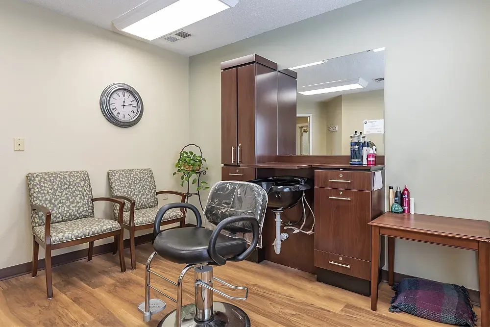 Hair salon waiting area with chairs, styling station, mirror, and wooden cabinets
