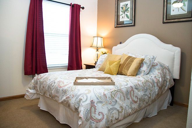 Cozy bedroom with a white bed, red curtains, bedside lamp, and framed wall art