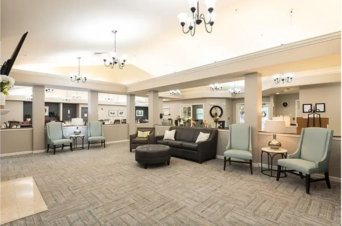 Spacious hospital or care facility lobby with sofas, chairs, tables, and chandeliers