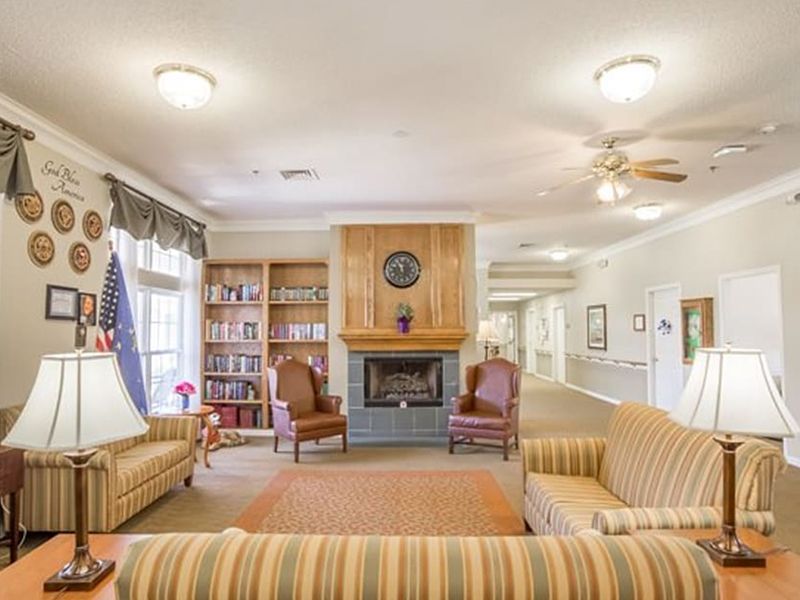 Bright lobby with beige sofas, armchairs, fireplace, lamps, and wall decor in a cozy sitting room