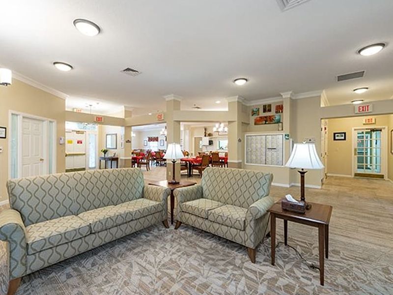Bright hotel lobby with patterned sofas, a lamp, tables, and open seating area