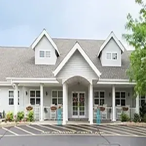 Front view of a gray house with white trim, gabled roof, porch, and parking spaces in front