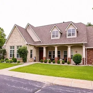 Suburban house with stone siding, dormer windows, and a front porch, bordered by a green lawn