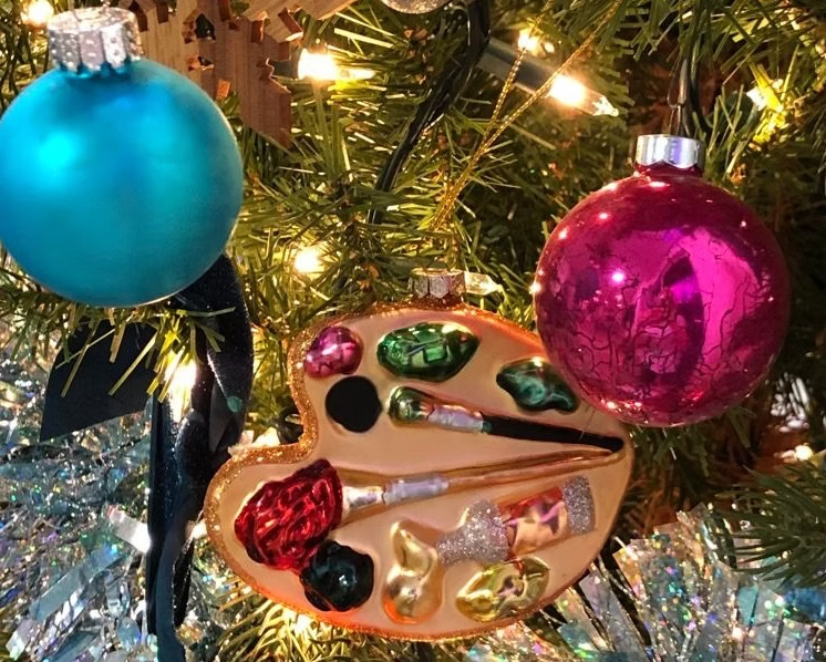 Christmas tree decorated with ornaments: teal ball, magenta ball, and artist's palette.