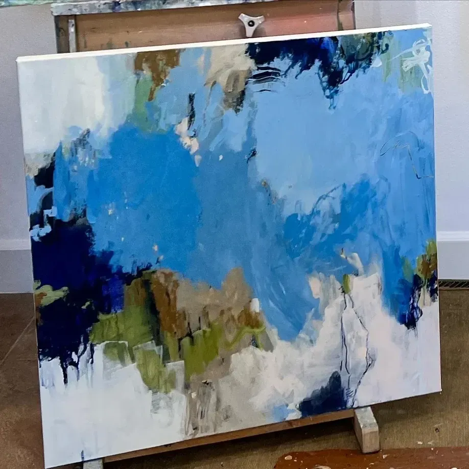 Abstract painting with blue, green, and brown brushstrokes on a canvas; set on an easel.
