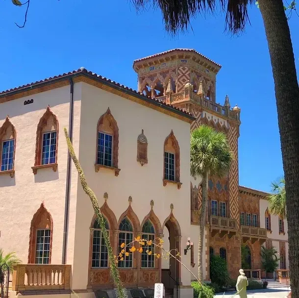 Tan and brown stucco building with arched windows and a decorative tower under a blue sky.