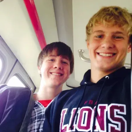 Two young men smiling, one in a hoodie with 