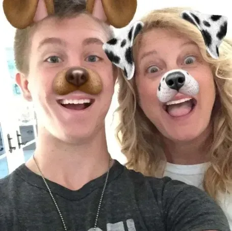 Two people wearing dog-themed Snapchat filters, smiling and looking at the camera.