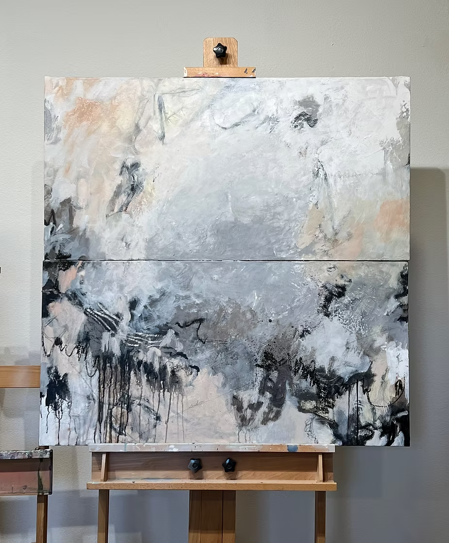 Abstract painting on a wooden easel, mostly neutral tones with black and peach accents.