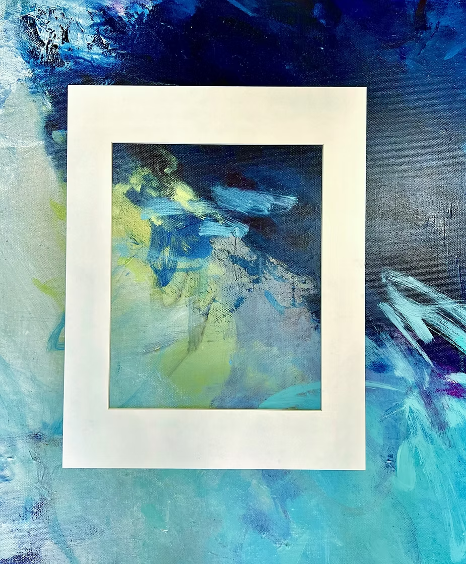 Small abstract painting in blue, green, and white, mounted on a white mat against a larger blue background.