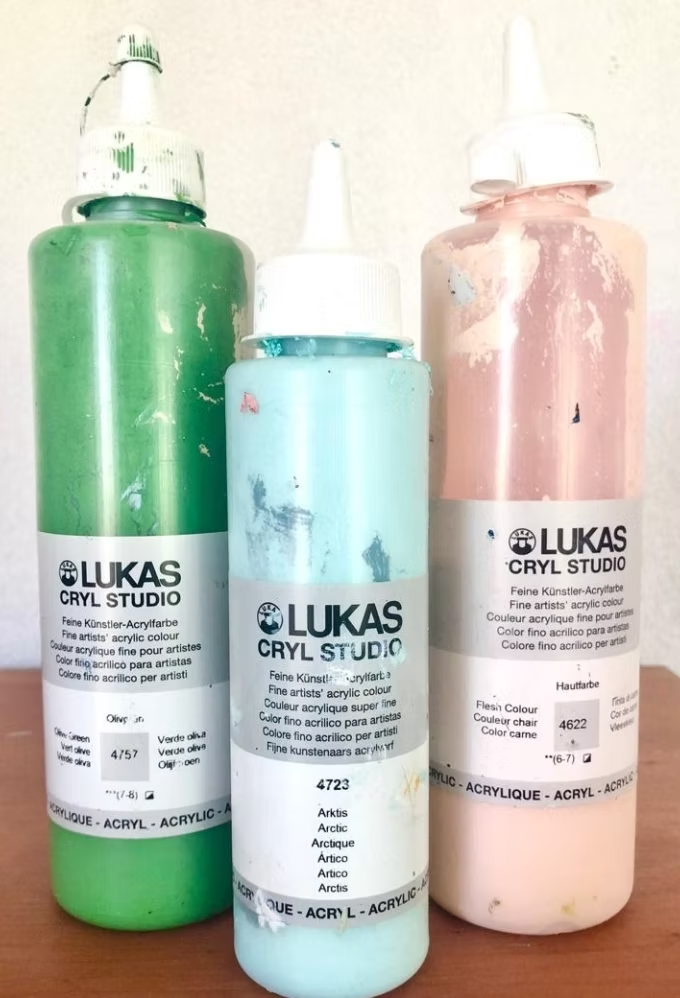 Three Lukas Cryl Studio acrylic paint bottles in green, blue, and peach colors.