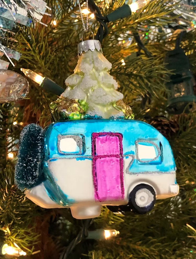Christmas tree ornament: blue and white camper with pink door, topped with a frosted green tree.