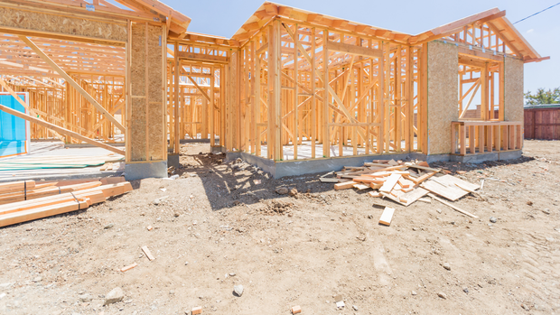 Building under construction with scaffolding and blue safety netting against a clear sky