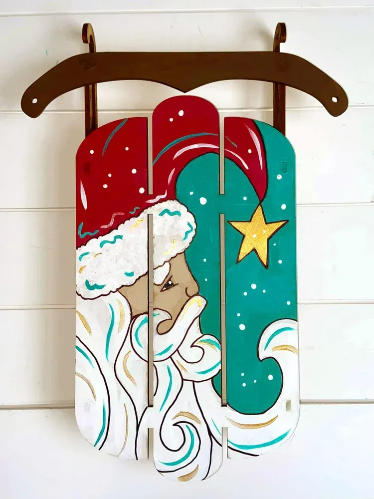 Colorful wooden wall art of a snowy Santa sleigh with red, teal, white, and gold details