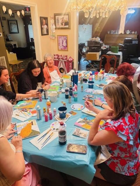 Friends seated around a turquoise table, painting and crafting at a birthday party in a decorated dining room