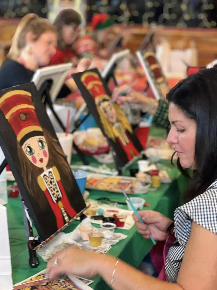People painting colorful matryoshka dolls at a craft workshop table