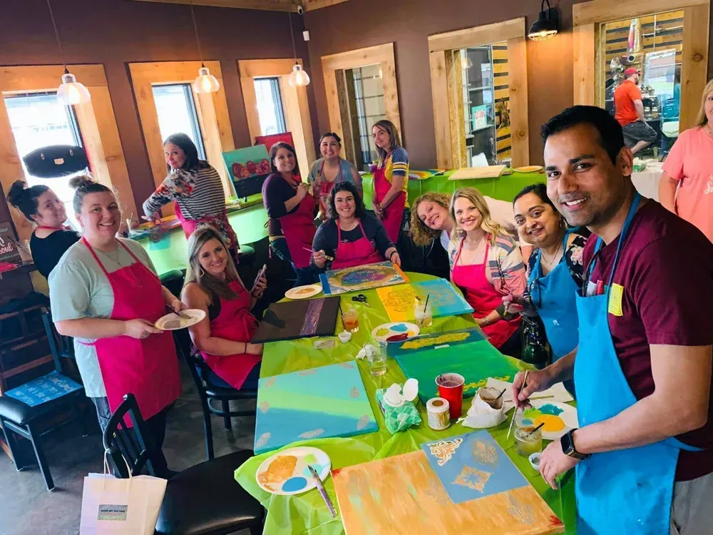 People gathered around a table with colorful craft supplies in a bright workshop room.