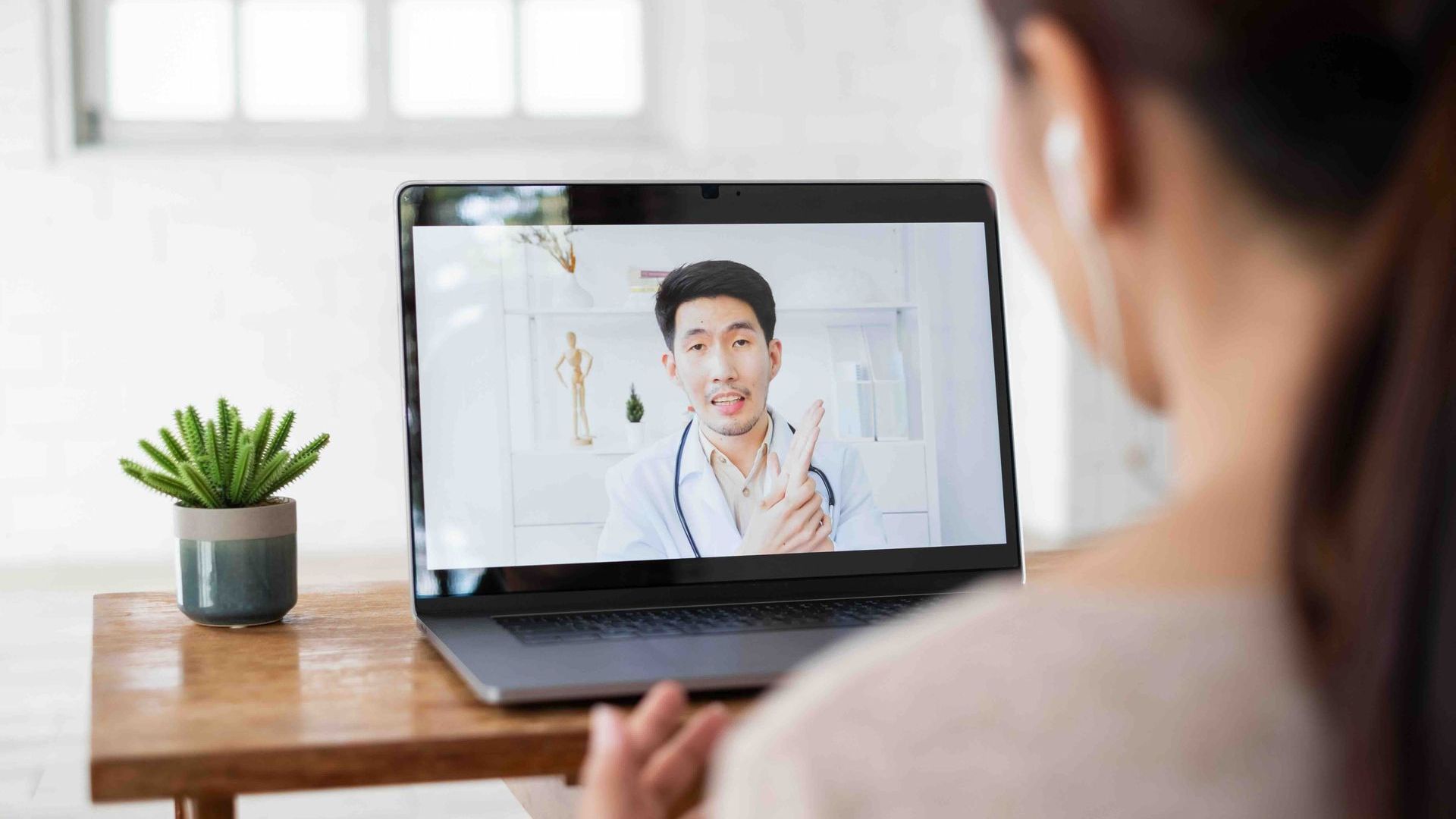 a woman is having a video call with a doctor on her laptop.