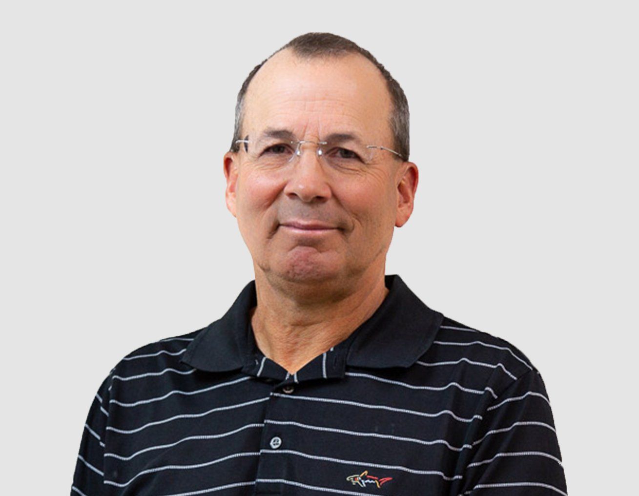 Dr. CR Barnett standing in front of a light gray wall