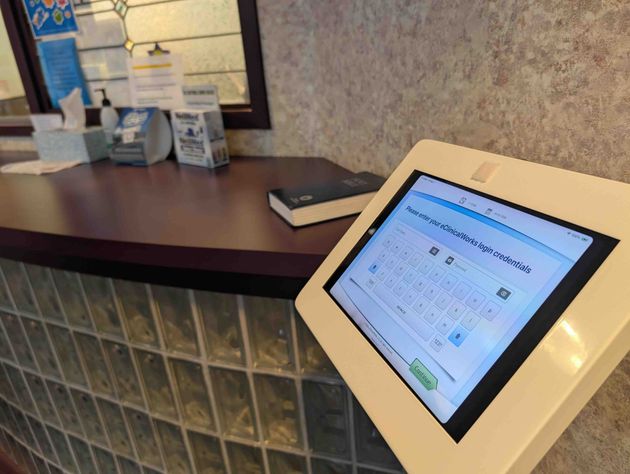 Lobby kiosk with touchscreen display beside a counter and glass block wall