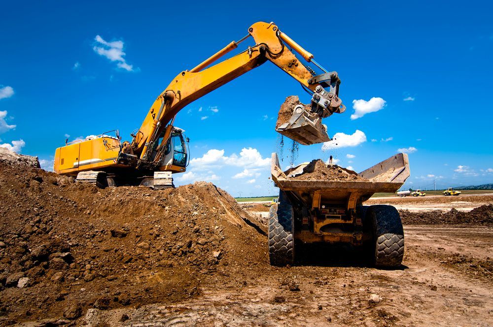 A Yellow Excavator is Loading Dirt Into a Dump Truck — Lantry Earthmoving in Phoenix Park, NSW