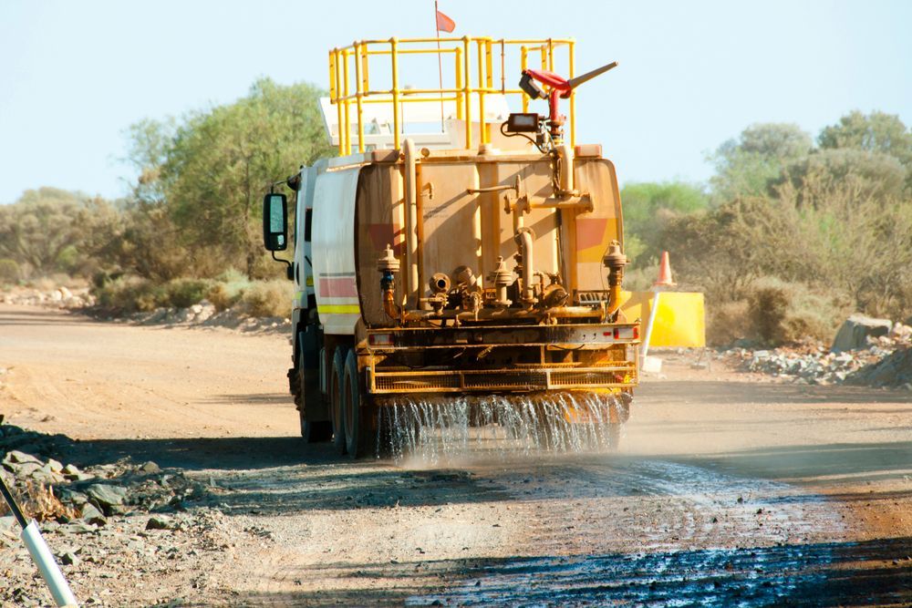 A Water Cart is Driving Down a Dirt Road — Lantry Earthmoving in Phoenix Park, NSW