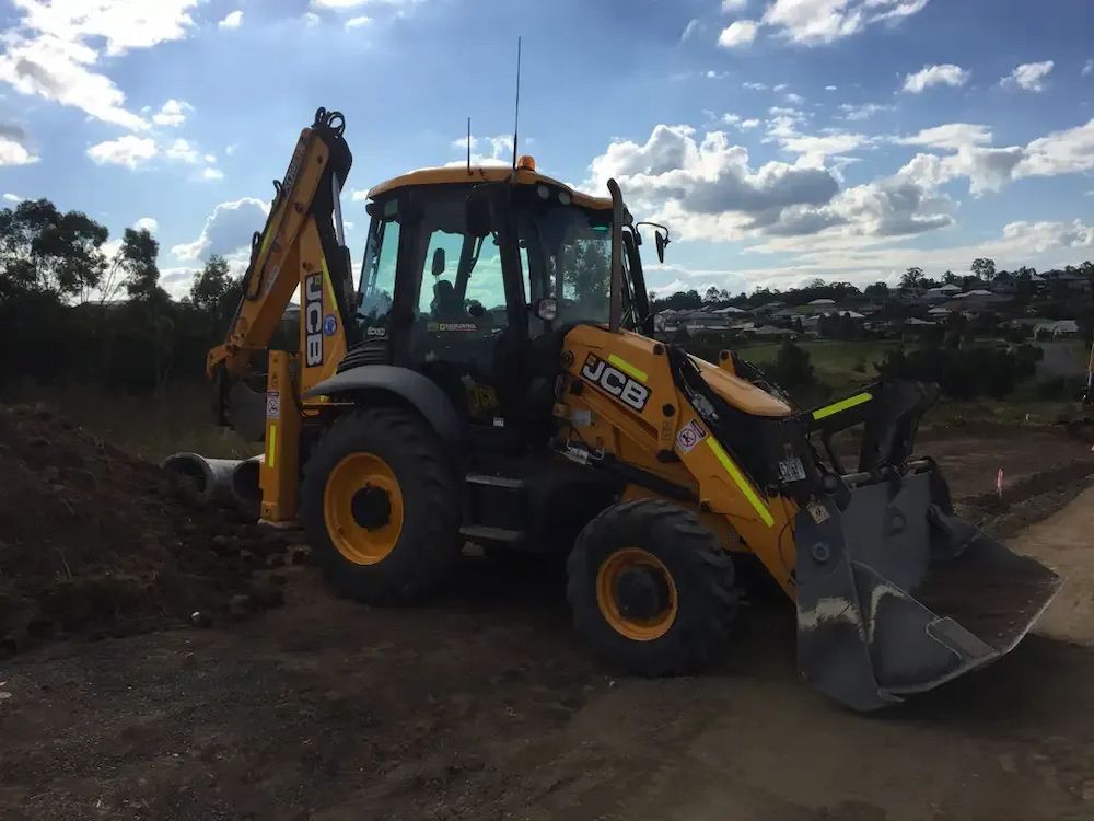A Yellow and Black Tractor is Parked on a Dirt Road — Lantry Earthmoving in Phoenix Park, NSW