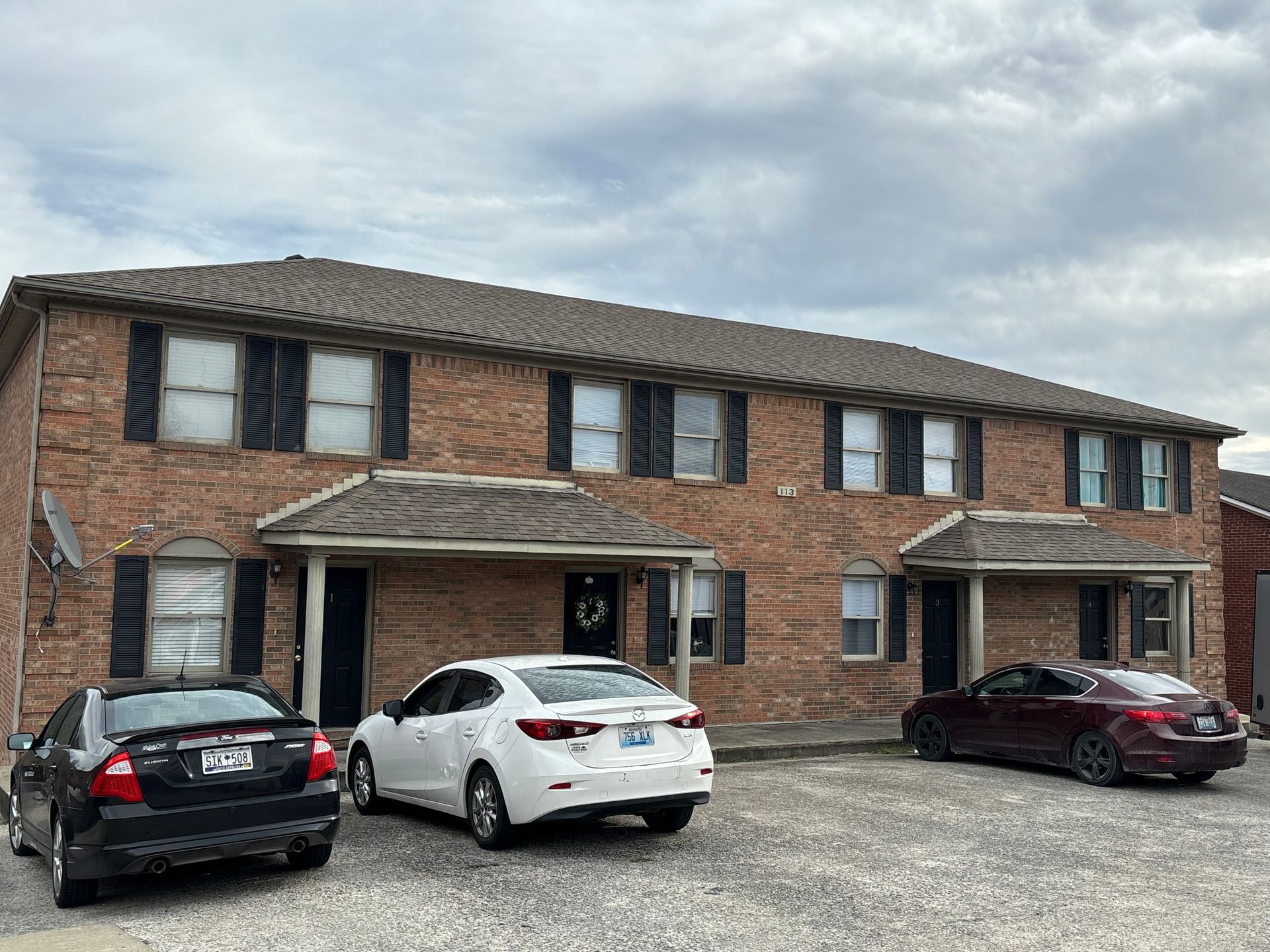 Two cars are parked in front of a brick building.