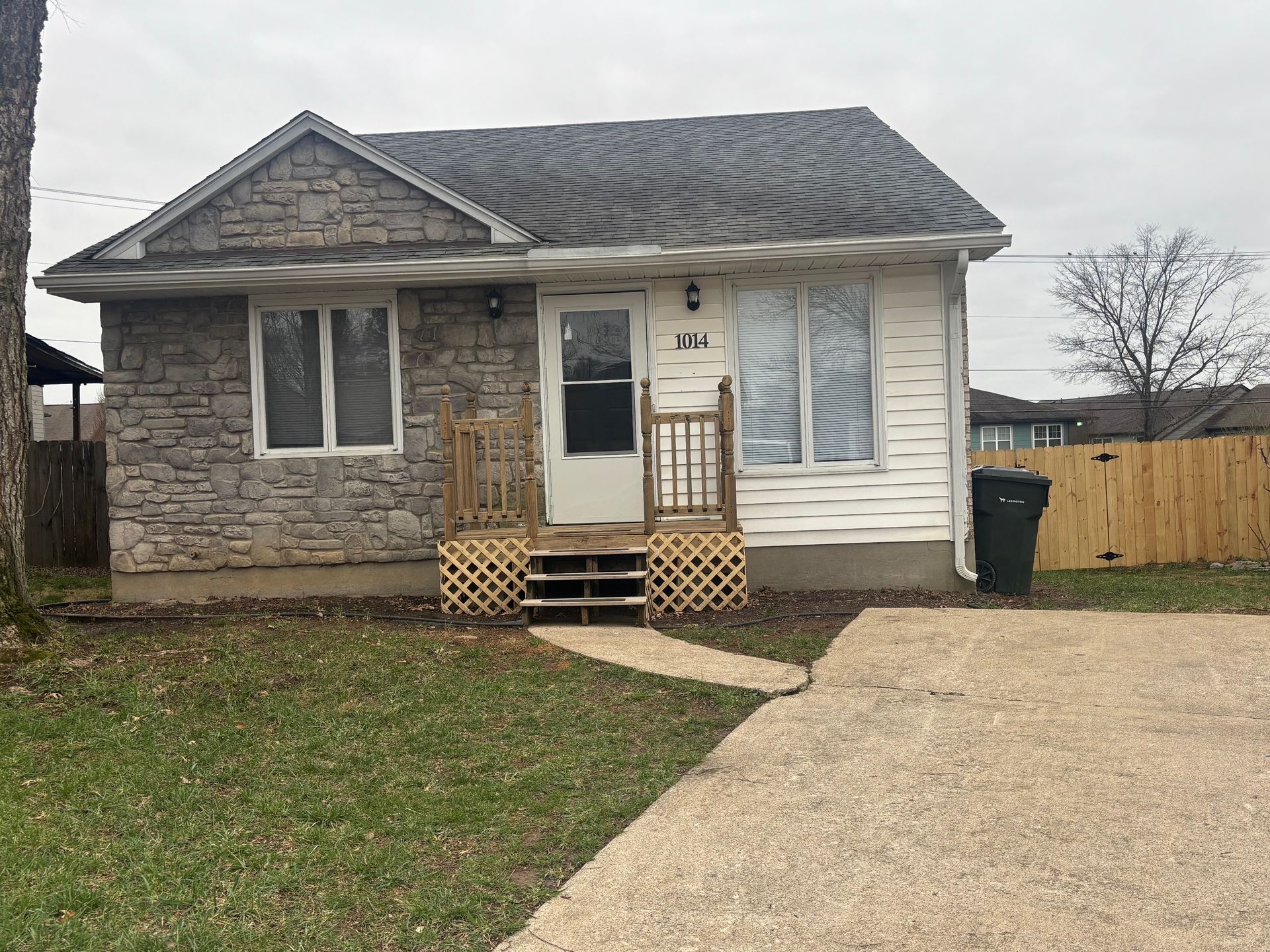 A small house with a porch and a driveway in front of it.