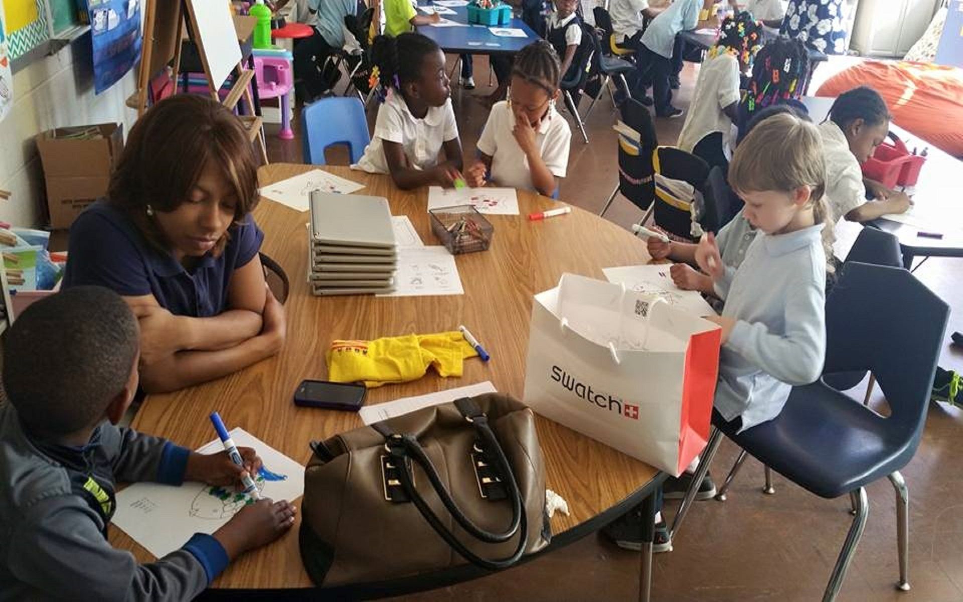 A group of children are sitting around a table with a bag that says supreme on it