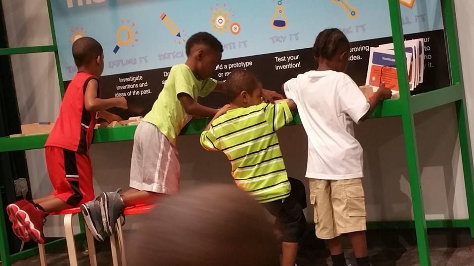 A group of young boys are looking at books on a table.