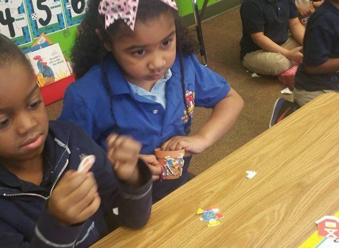Children seated at a table, playing with small pieces during a classroom activity.